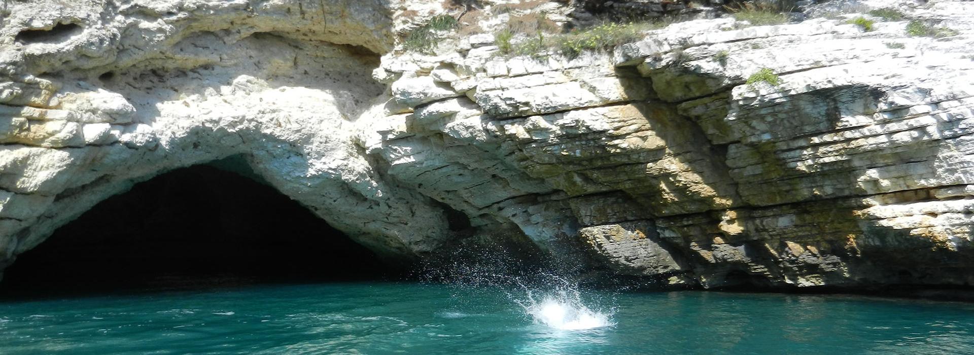 Grotta marina con acqua turchese e spruzzi d'acqua.