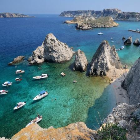 Scogli, barche e acqua cristallina in una baia pittoresca.