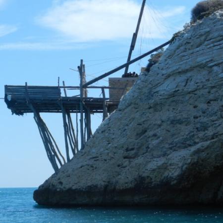 Struttura di legno su scogliera, probabilmente un trabucco, affacciata sul mare.