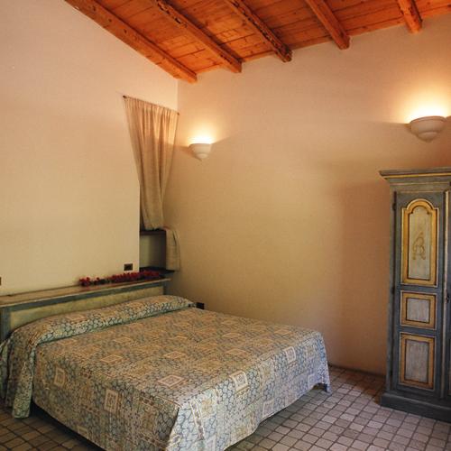 Camera accogliente con letto matrimoniale, armadio antico e finestra aperta.